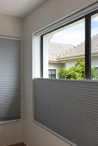 Grey honeycomb blinds on a tall side window and a lower half window