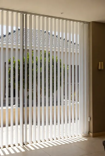 White vertical blinds across a tall glass sliding door
