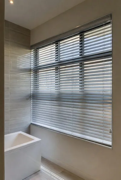 Grey aluminium venetian blinds on a large bathroom window beside a bath
