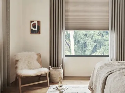 Honeycomb cellular blind half lowered in a bedroom with floor-length curtains
