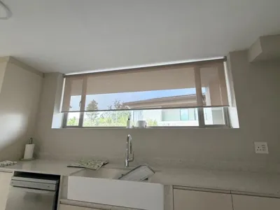 Roller blind half lowered over a wide kitchen window above the sink