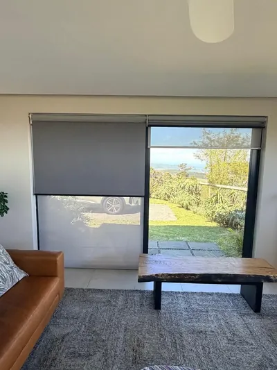 Grey duo roller blinds working independently over living room sliding doors