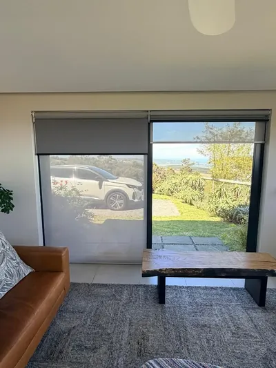 Duo roller blinds over living room sliding doors, grey blockout and sheer layers