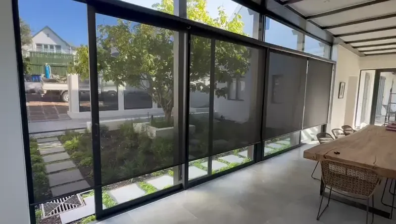 Charcoal sheer roller blinds raising on their own across a patio sliding door