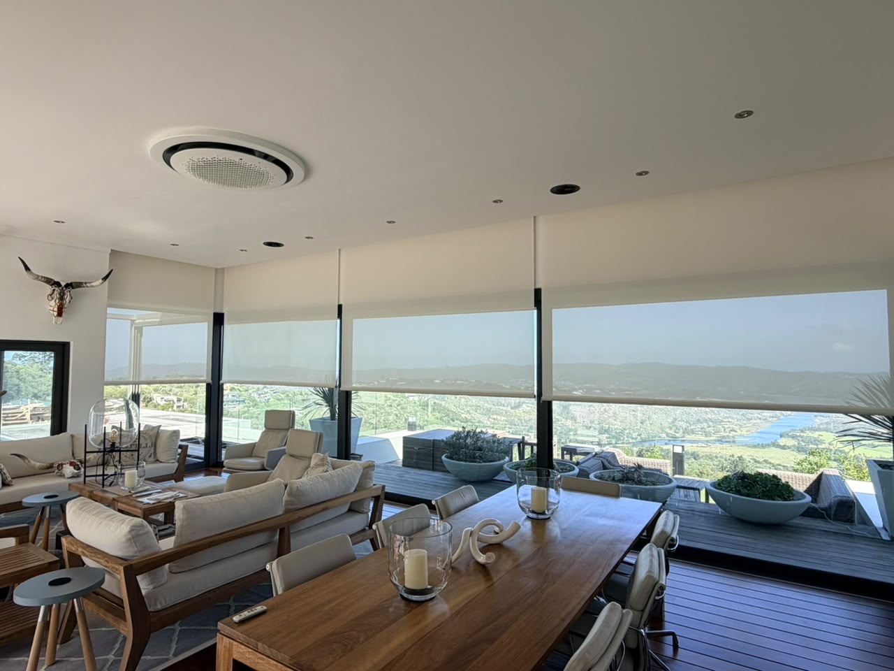 Custom Blinds Pearl White roller blinds across a bright living and dining room in South Africa