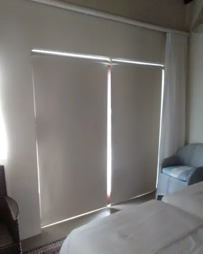 Two cream blockout roller blinds over bedroom sliding doors