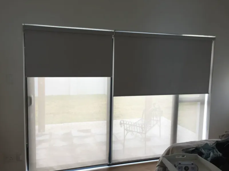 Two charcoal duo roller blinds side by side over patio doors, blockout over sheer