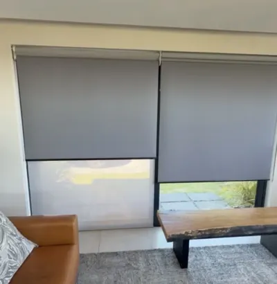 Two grey duo roller blinds with sheer layer showing below, living room
