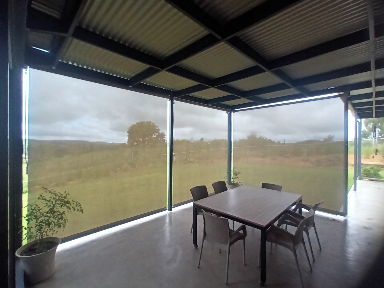 Outdoor screen blinds in Almond sheerweave fully down on farmhouse patio with dining table