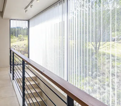 White vertical blinds along a balcony walkway with garden view