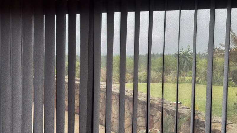Vertishades dim out Fossil panels open showing garden and stone wall view